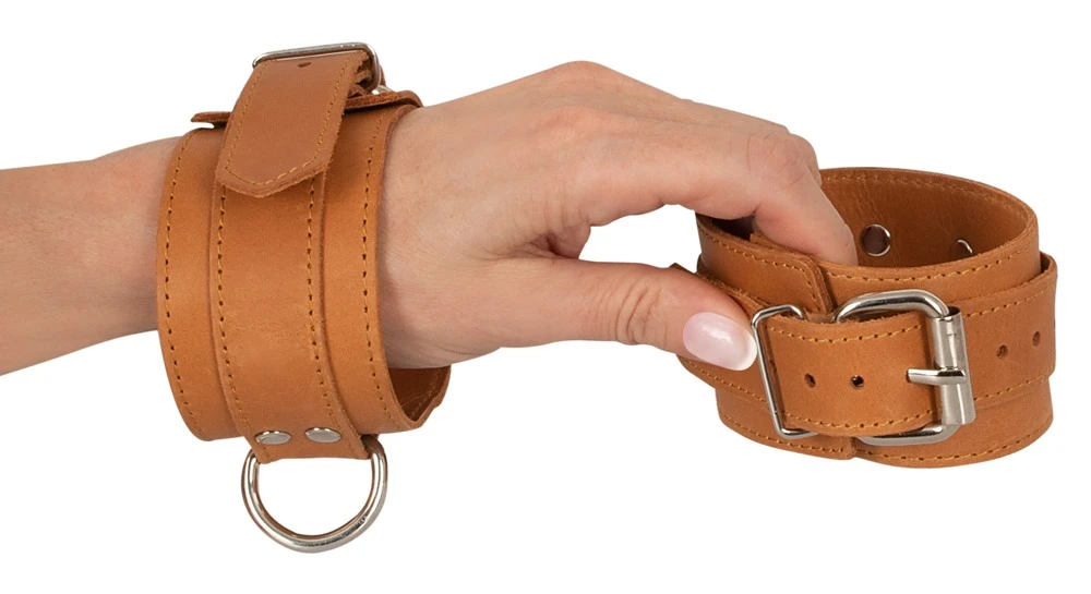 Stabile, hochwertige Handfesseln von ZADO aus glattem Leder in typischer Naturoptik mit silberfarbenen Metalldetails und D-Ringen.